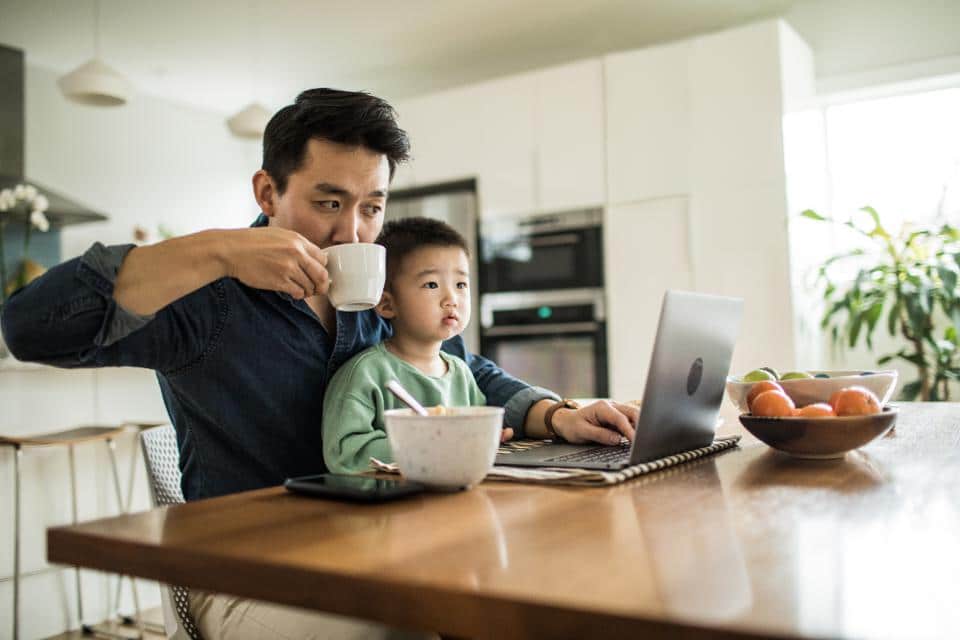 photo of a man working from home with his child