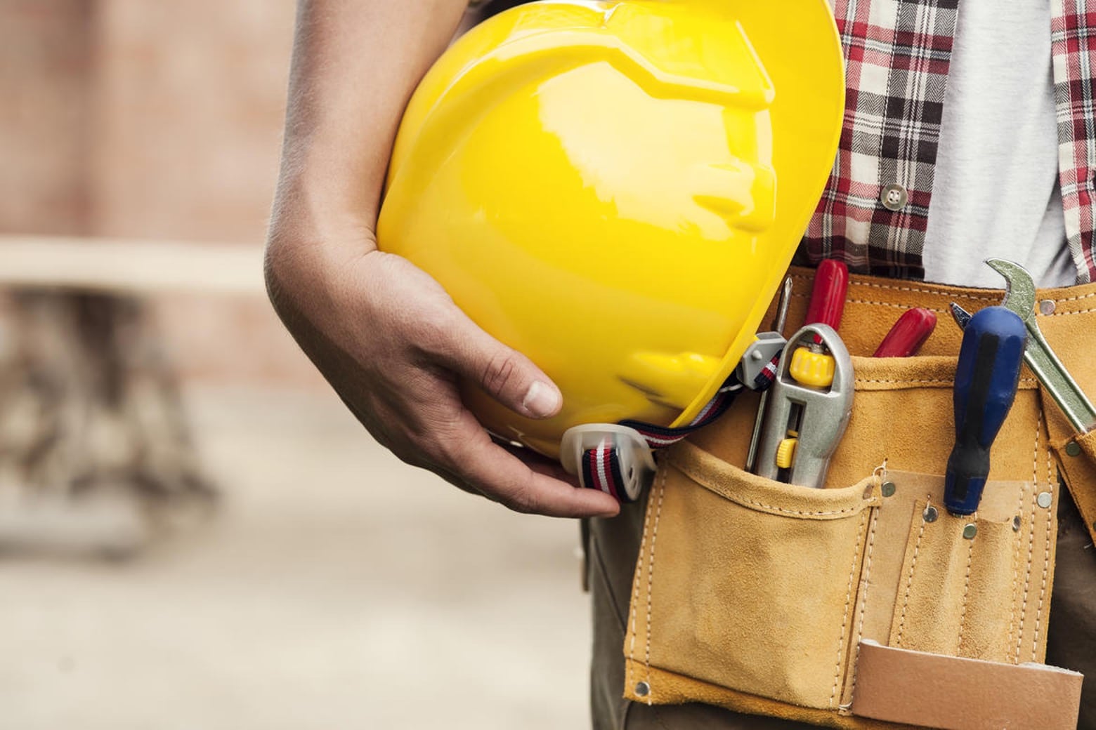 photo of a manual laborerer holding a yellow hard hat